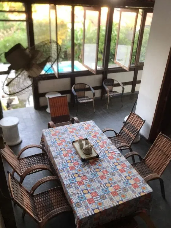 Espaço de convivência com mesa e janelas voltadas para a piscina